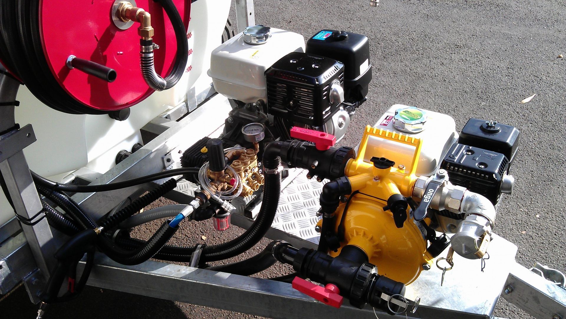 A yellow pump is attached to a trailer with a gas engine.