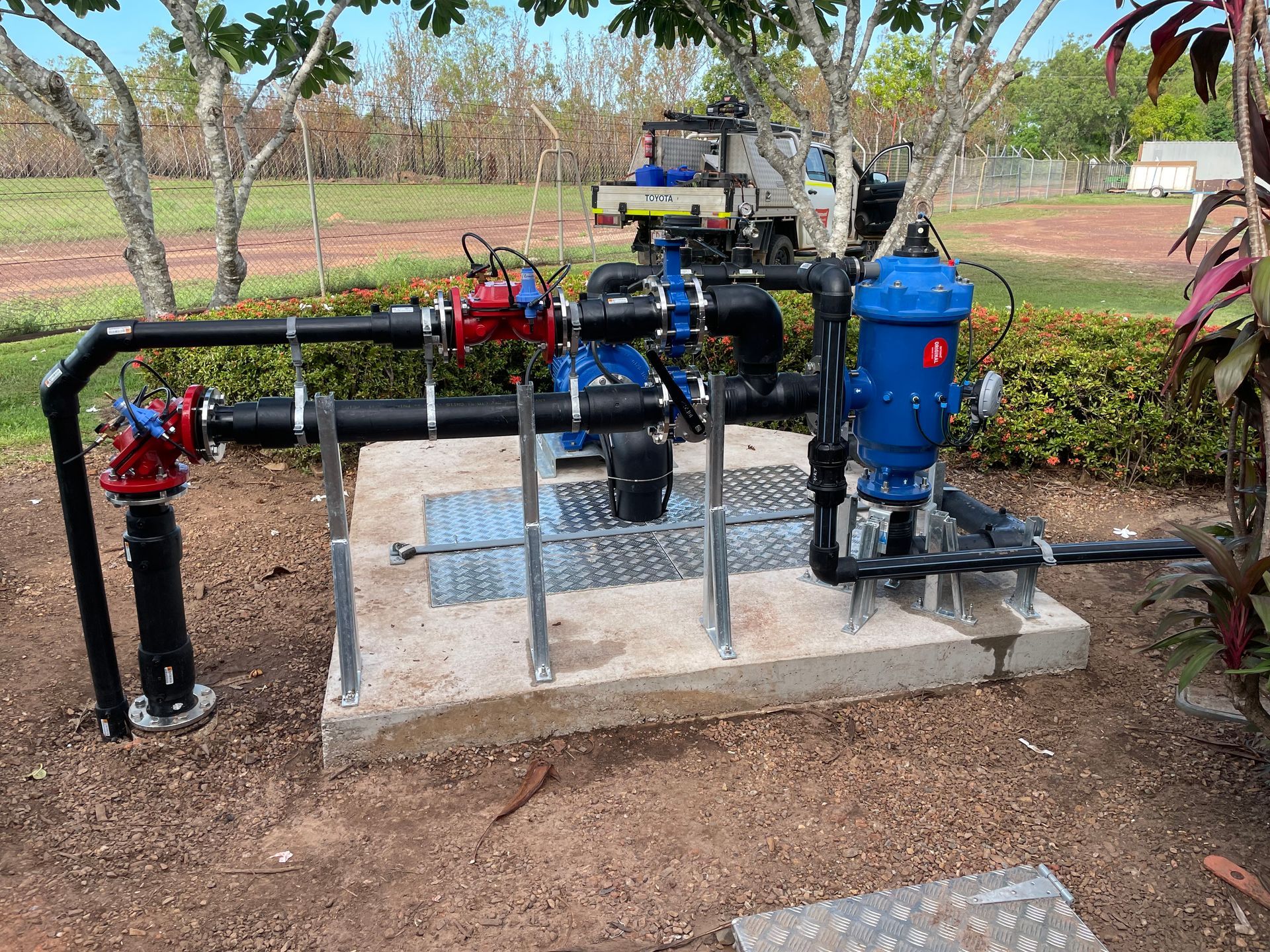 A water pump is sitting on top of a concrete platform next to a tree.