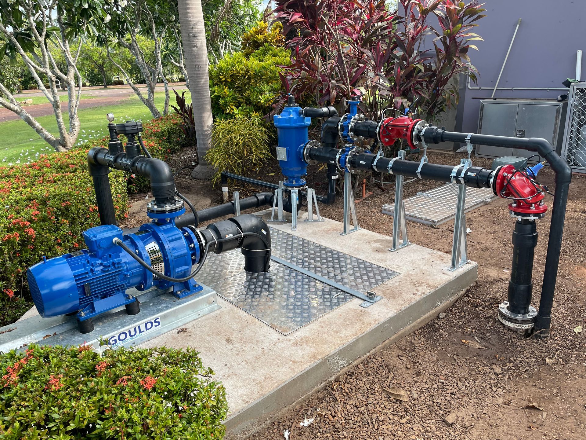 A blue pump is sitting on top of a concrete platform next to a bunch of pipes.