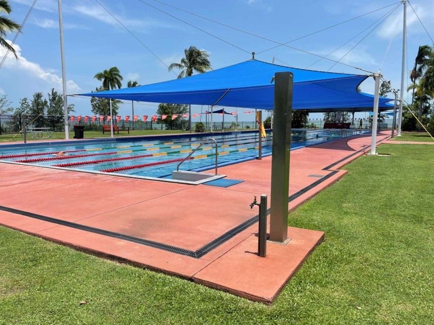 A swimming pool with a blue umbrella over it