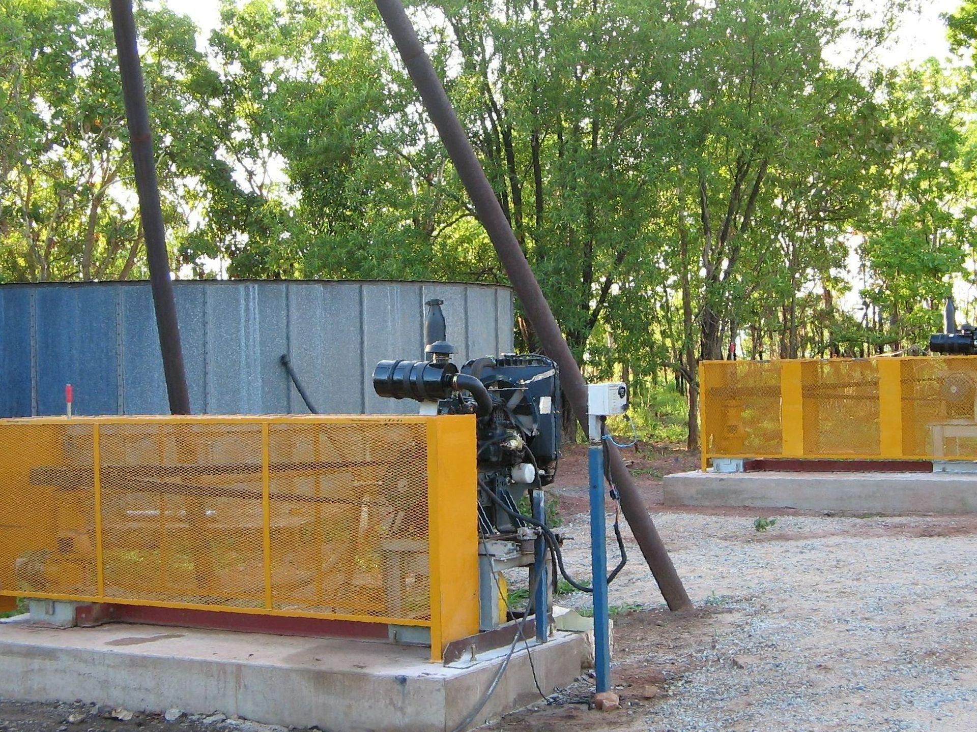 A yellow fence surrounds a machine in a field