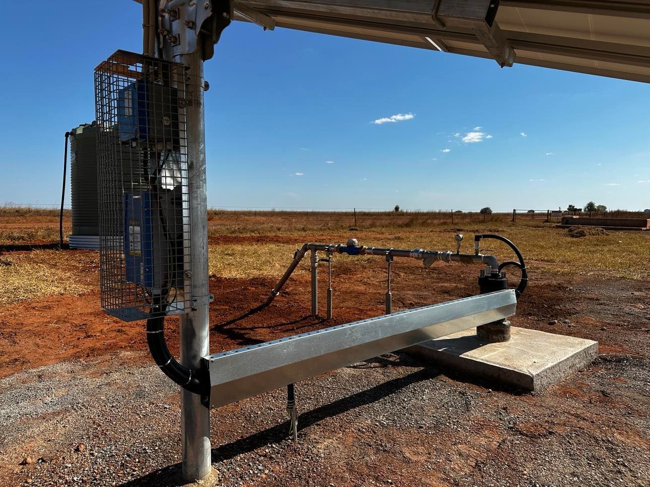 A metal pole is sitting in the middle of a dirt field.
