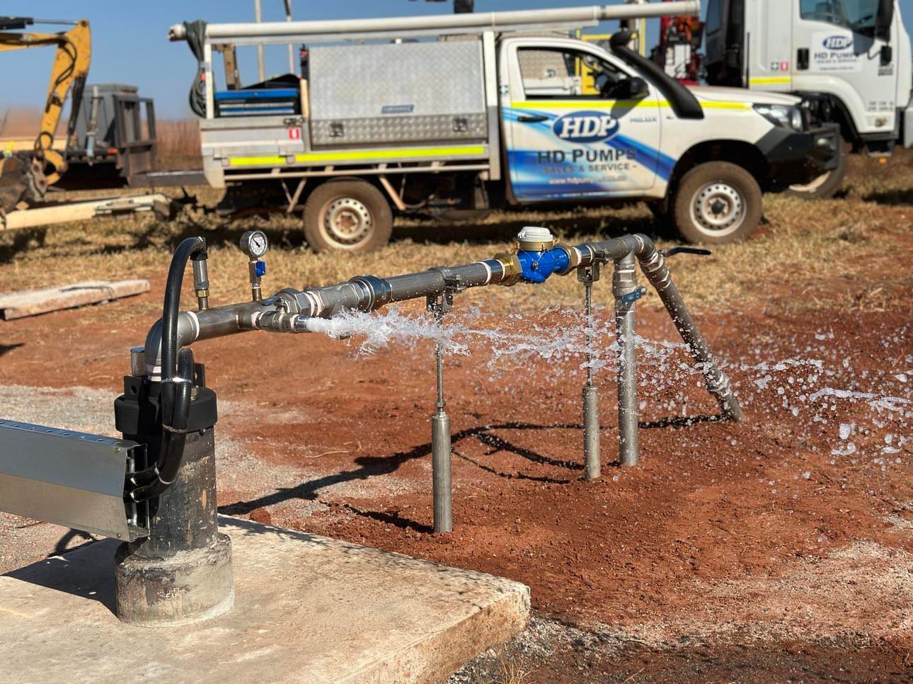 A white truck with the word hdp on the side is parked next to a water pump.