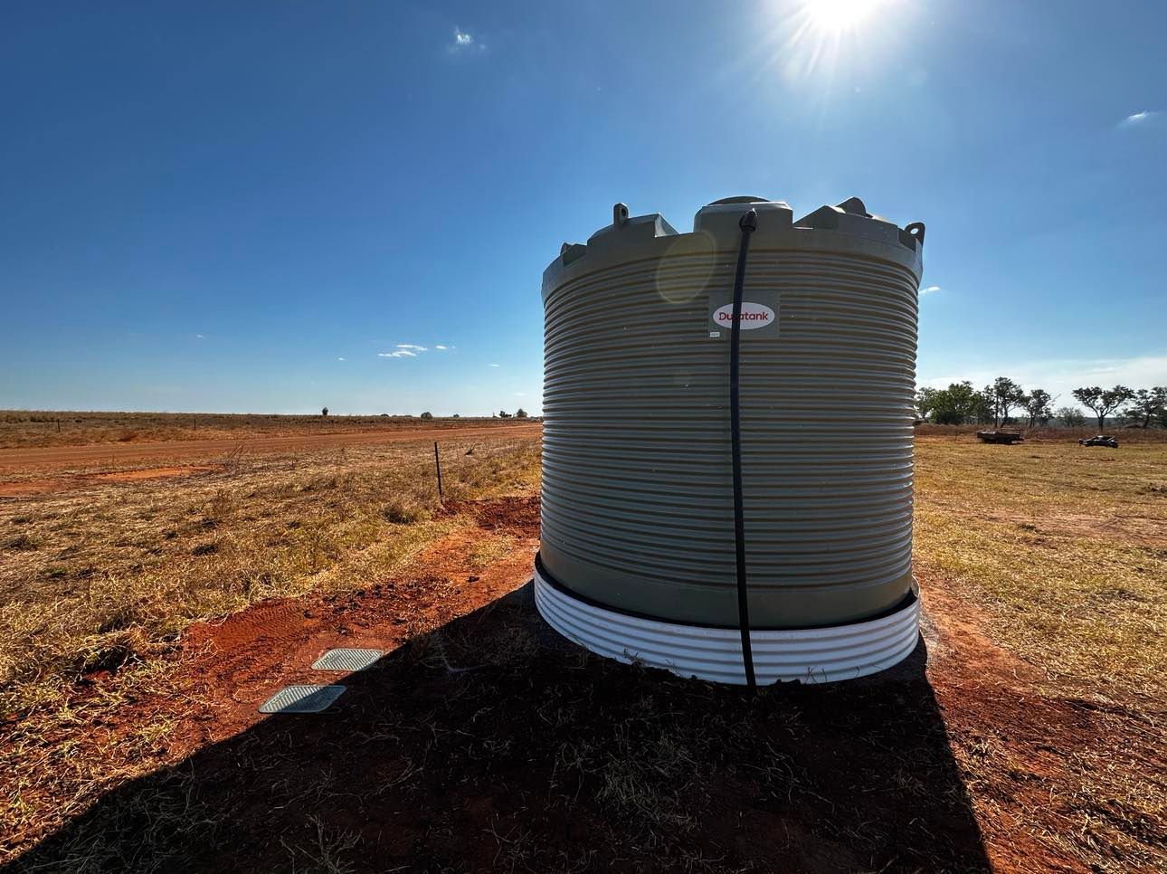 A large water tank is sitting in the middle of a field.