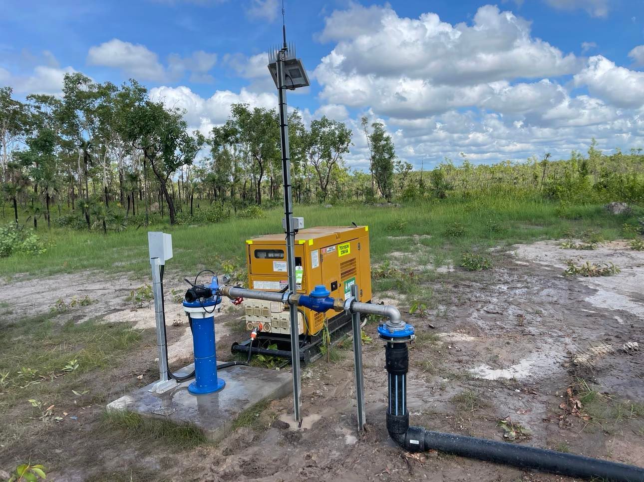 A water pump is sitting in the middle of a field.