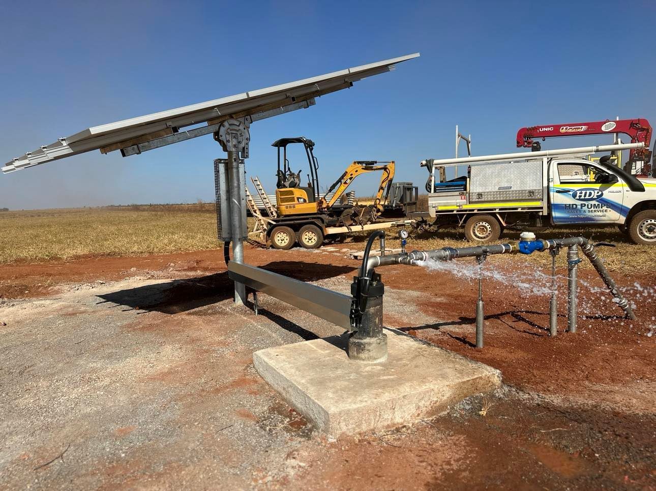 A truck is parked next to a solar panel in a field.