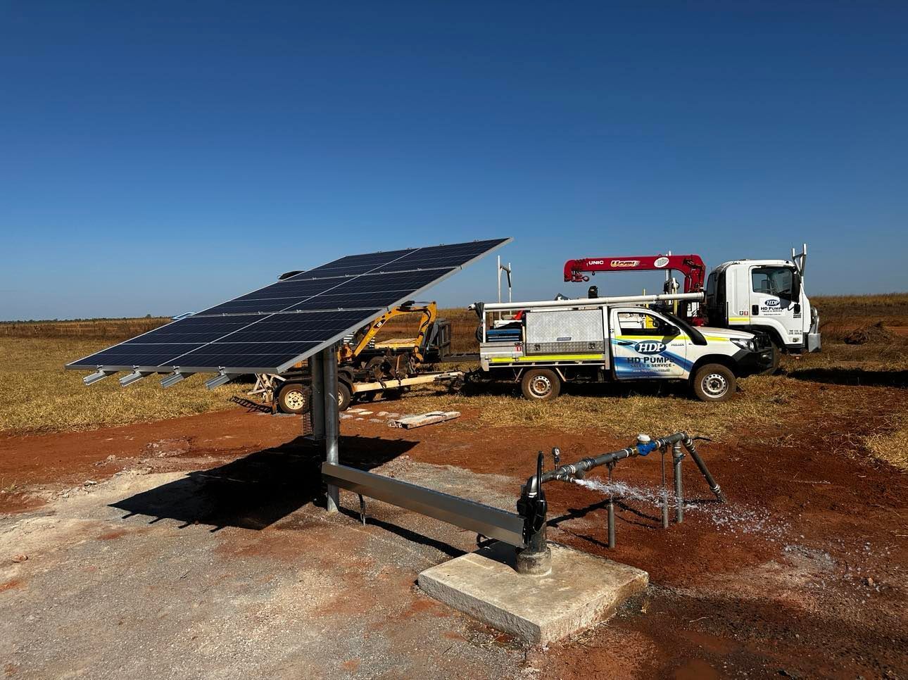 A truck is parked next to a solar panel in a field.