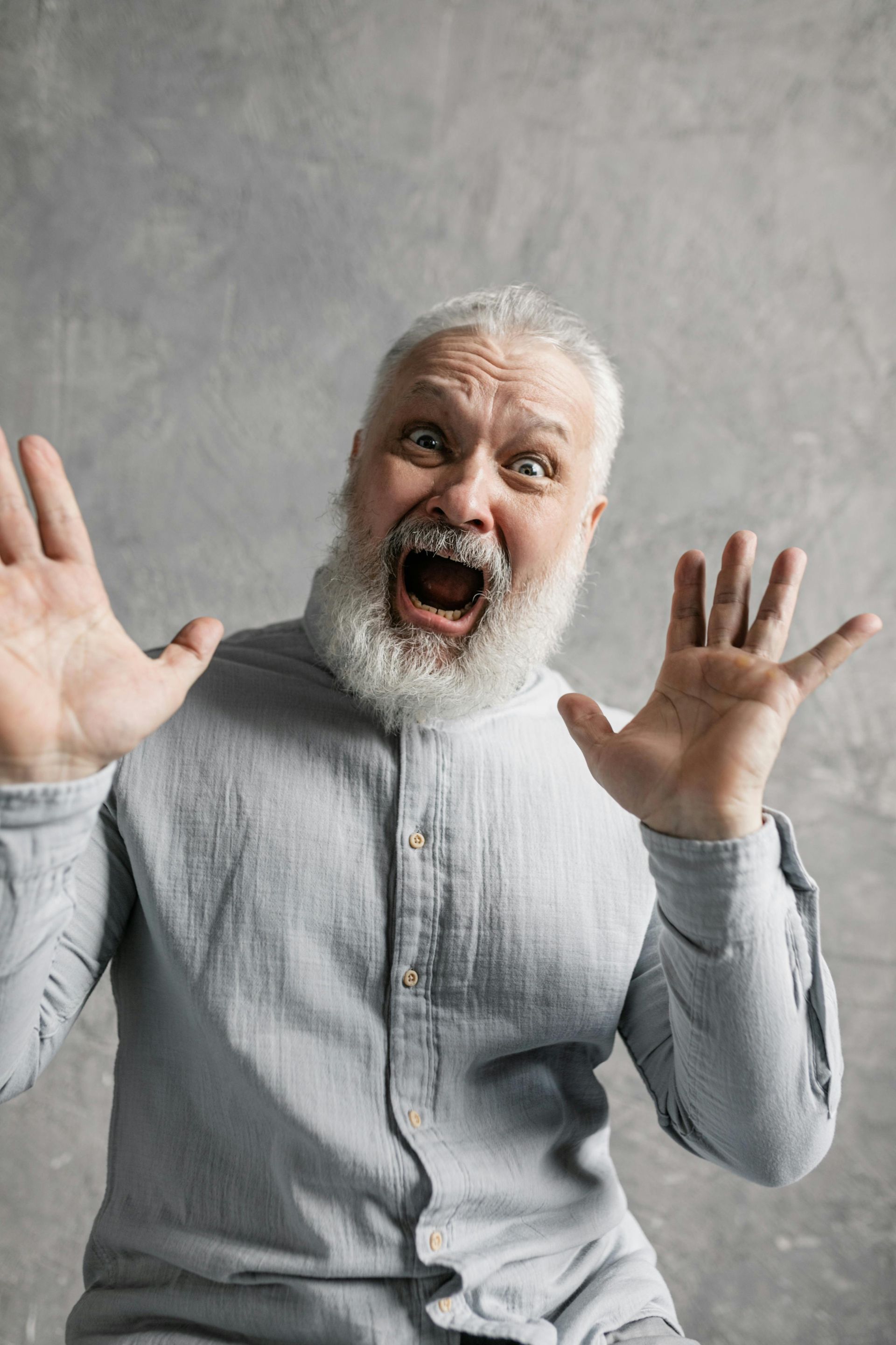 A man with a beard is making a shocked face with his mouth open.