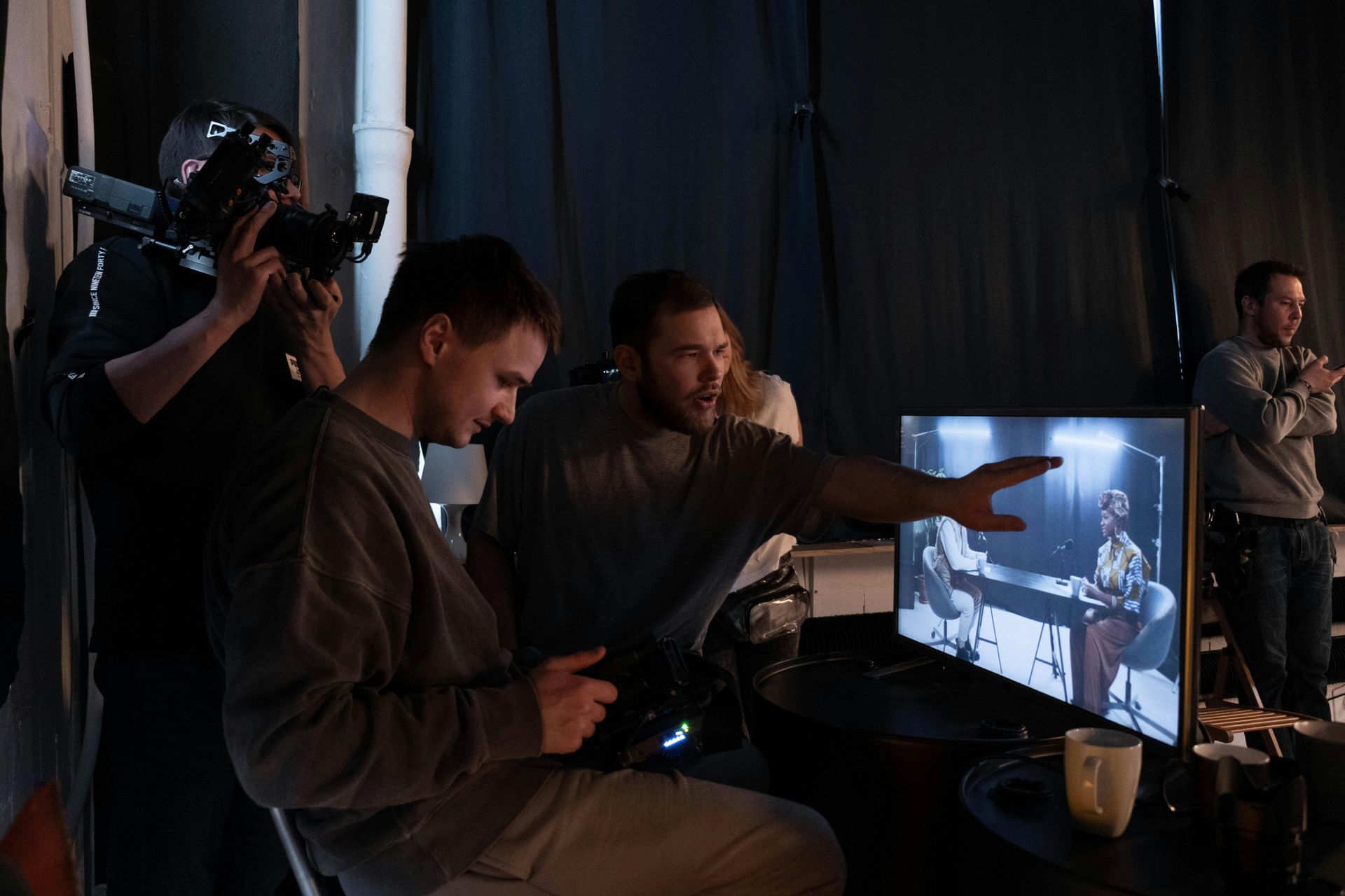 A group of men are watching a video monitor screen while filming.