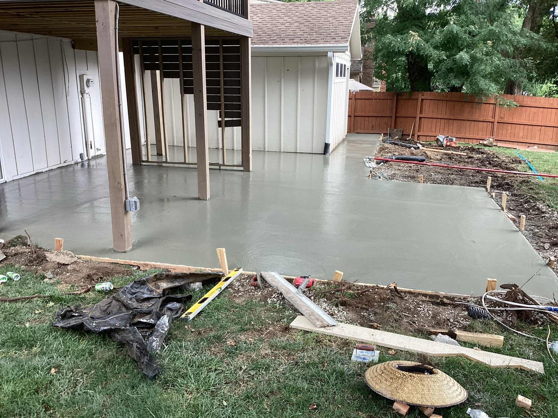 Construction site with concrete foundation and wooden forms, dirt, and nearby houses.