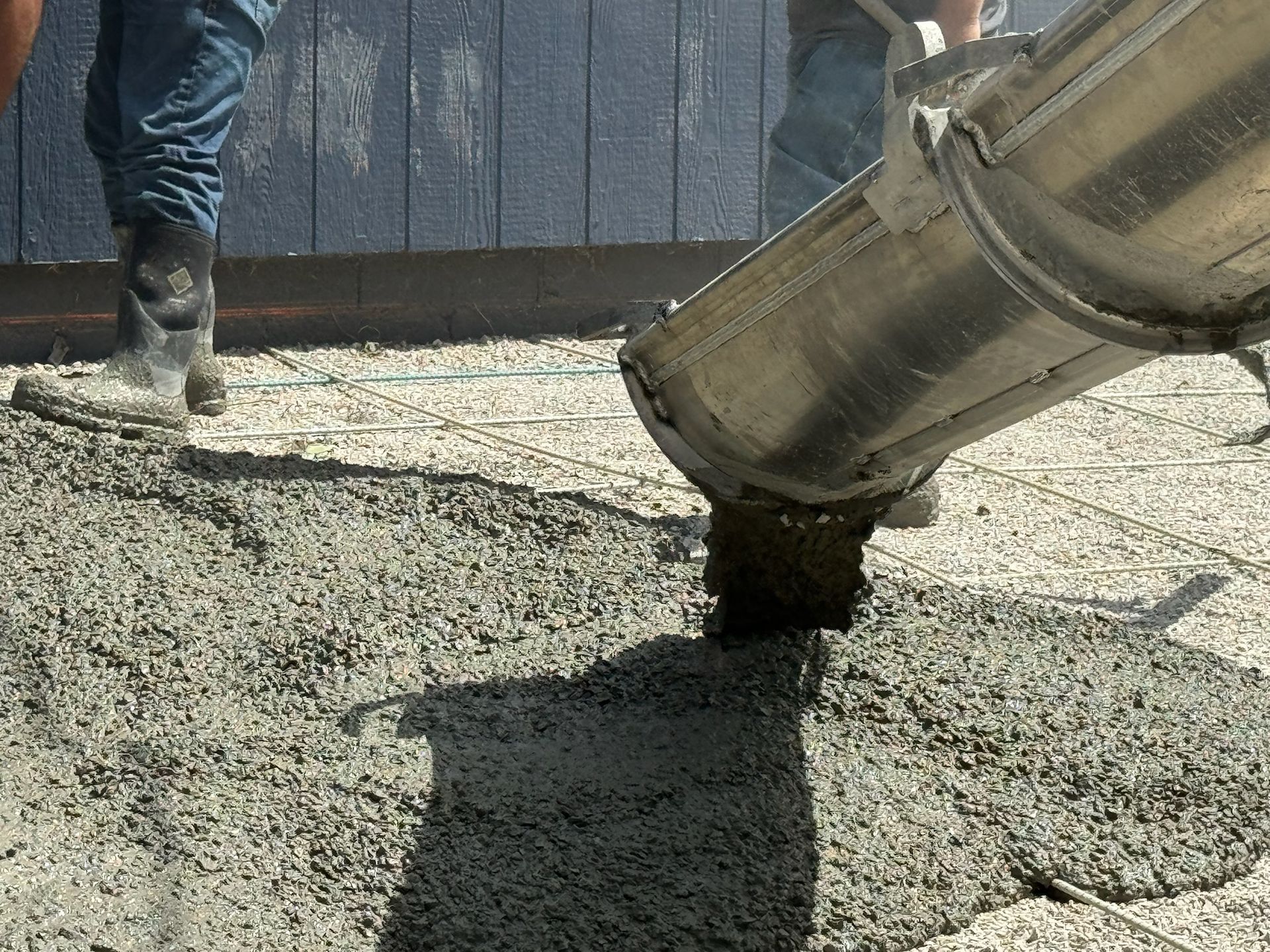 Concrete being poured from a metal chute onto a construction site.