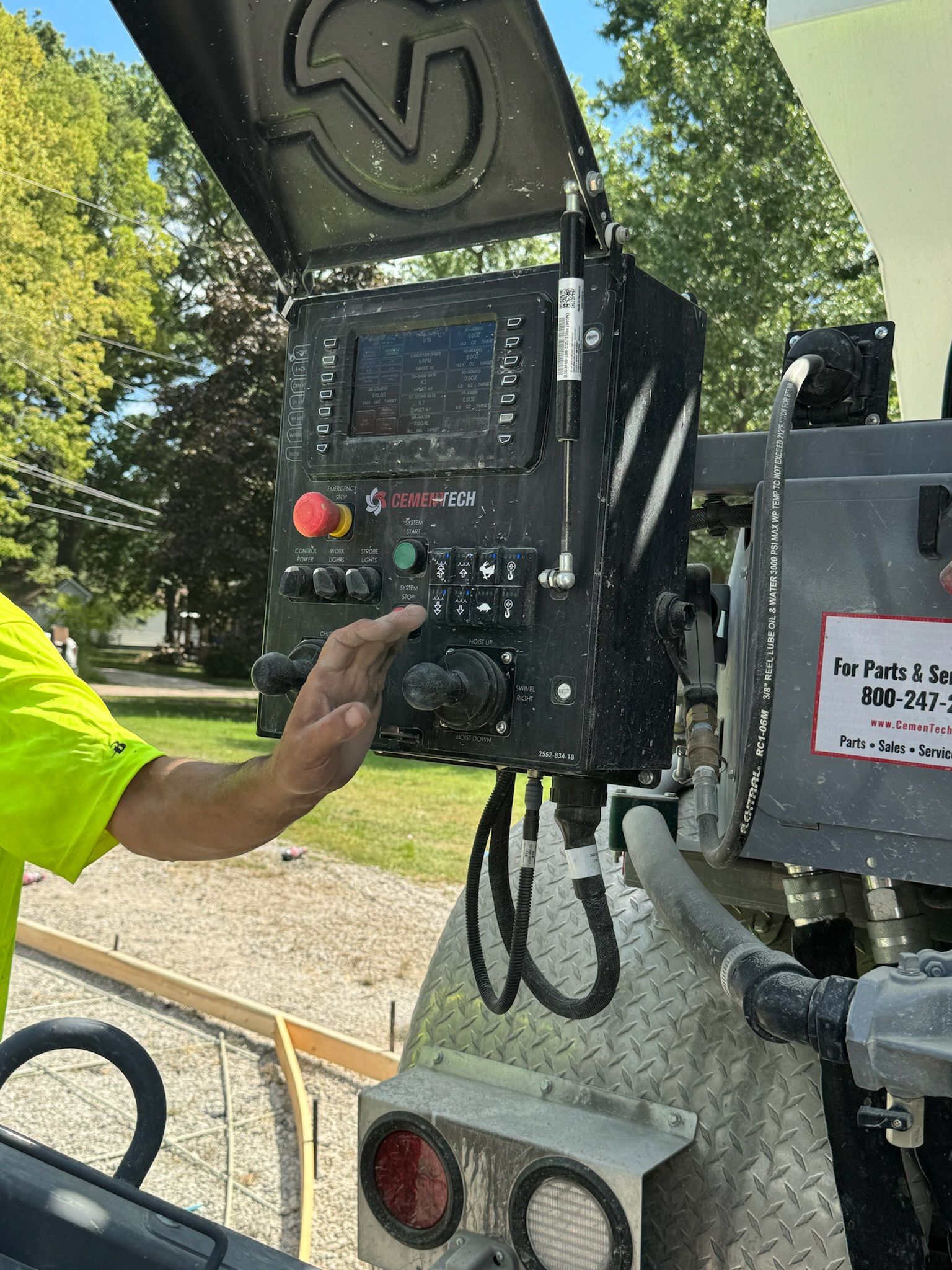 A person in a bright yellow shirt operates a piece of industrial equipment, adjusting controls on a black panel.