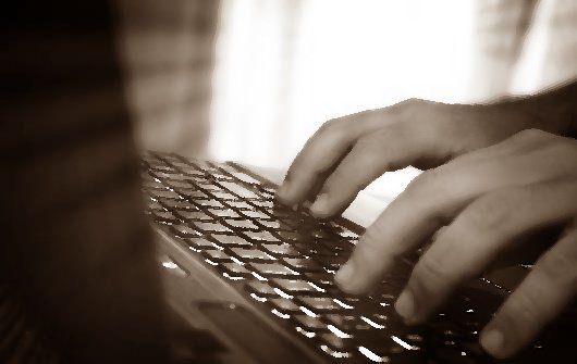 Hands type on computer keyboard