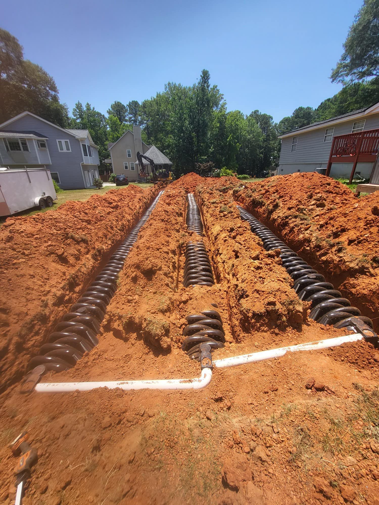 Trenches dug for a septic system installation, showing black coiled pipes