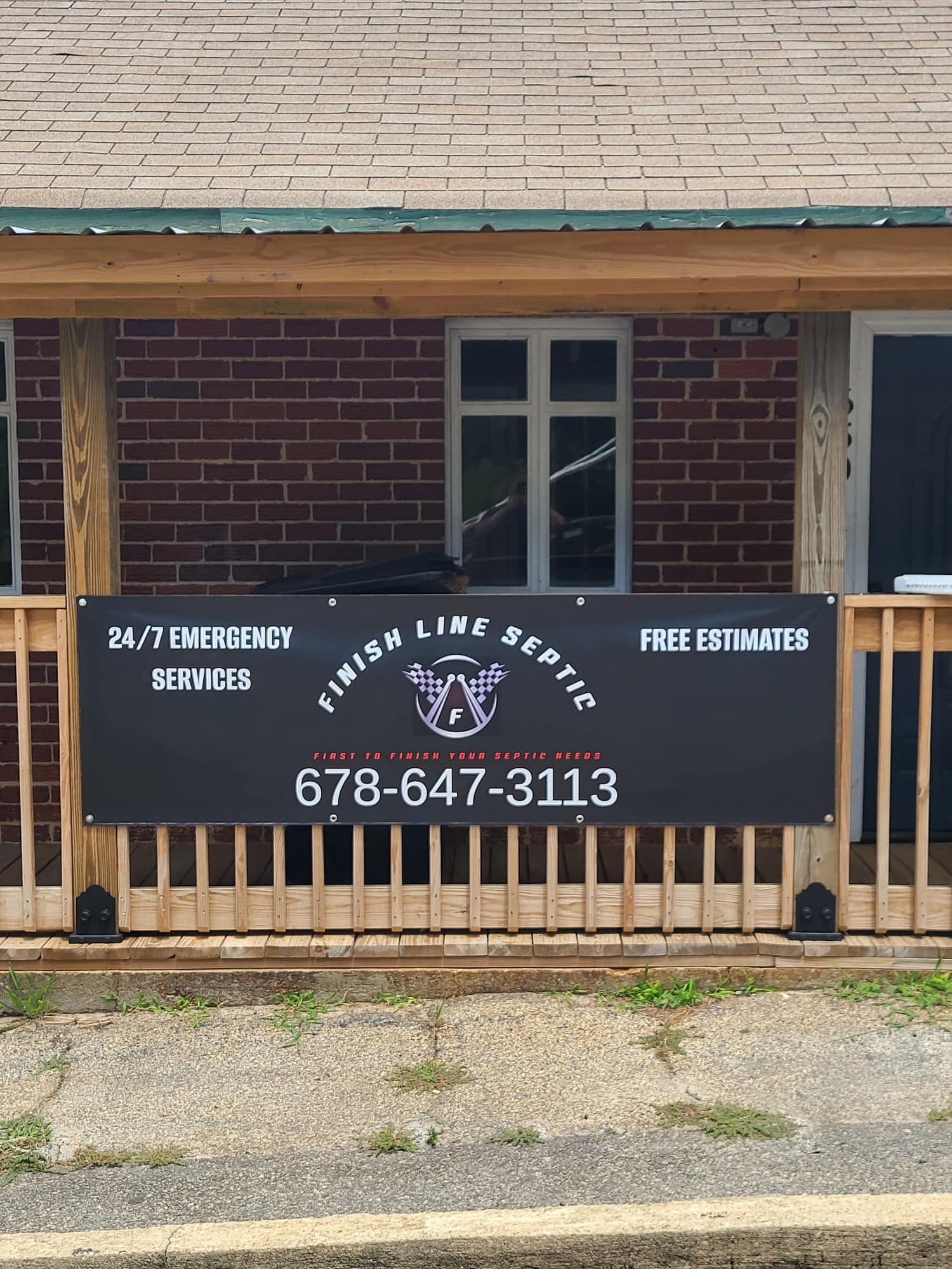 A banner for Finish Line Septic services is displayed on a brick building's porch.