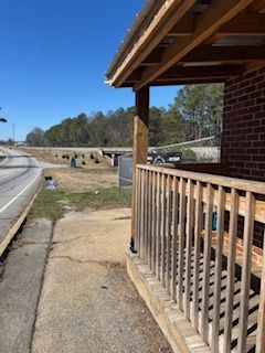 Exterior view with porch, road, and bridge in a rural area under a clear blue sky. Brick building.