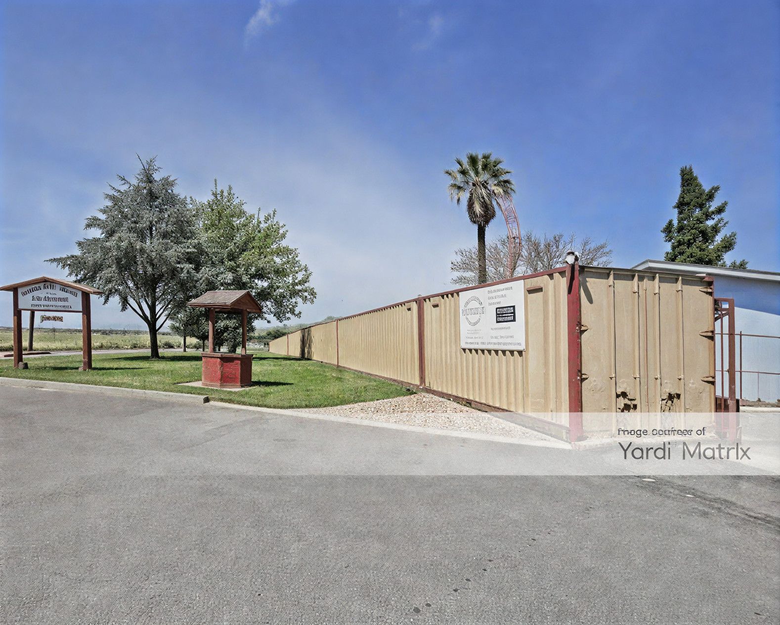 Storage facility with tan wooden fence and driveway, sunny day.