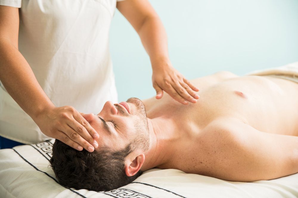 Female Therapist Using Her Hands For Some Reiki Therapy On A Young Man In A Holistic Spa — Restorative Natural Therapies in Kincumber, NSW