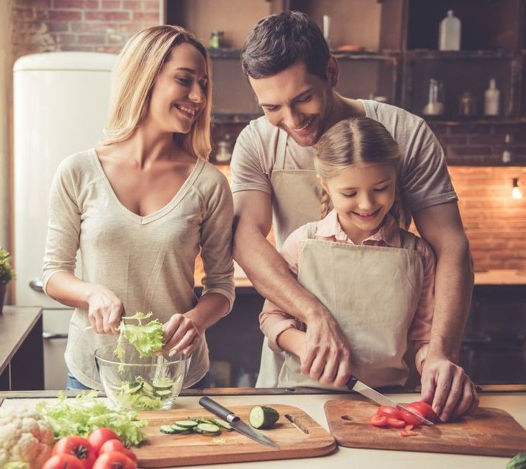 Girl With Her Parents Cutting Vegetables In The Kitchen — Dieticians, Herbalists & Naturopaths in Kincumber, NSW