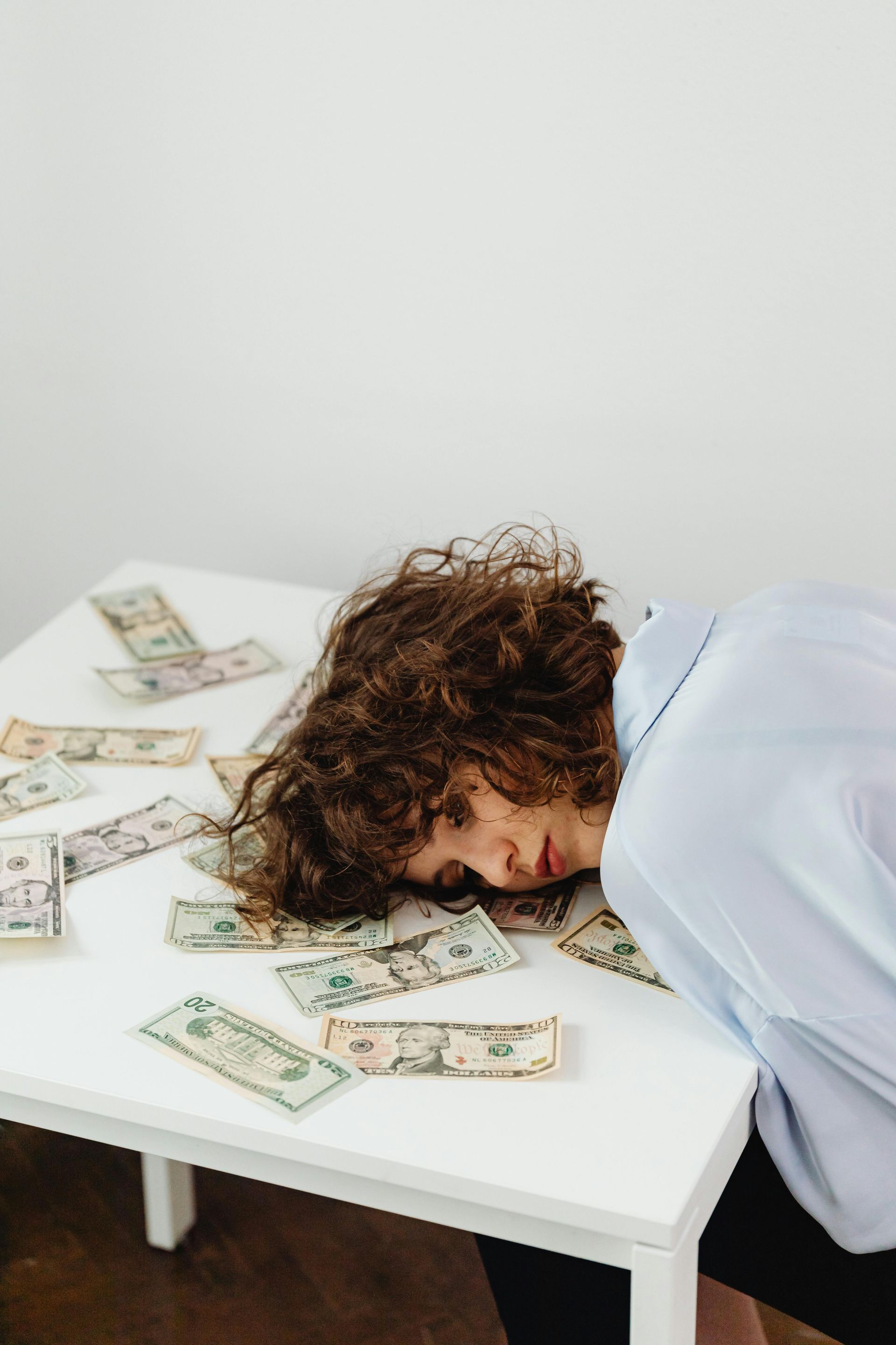 A woman is laying on a table with money on it.