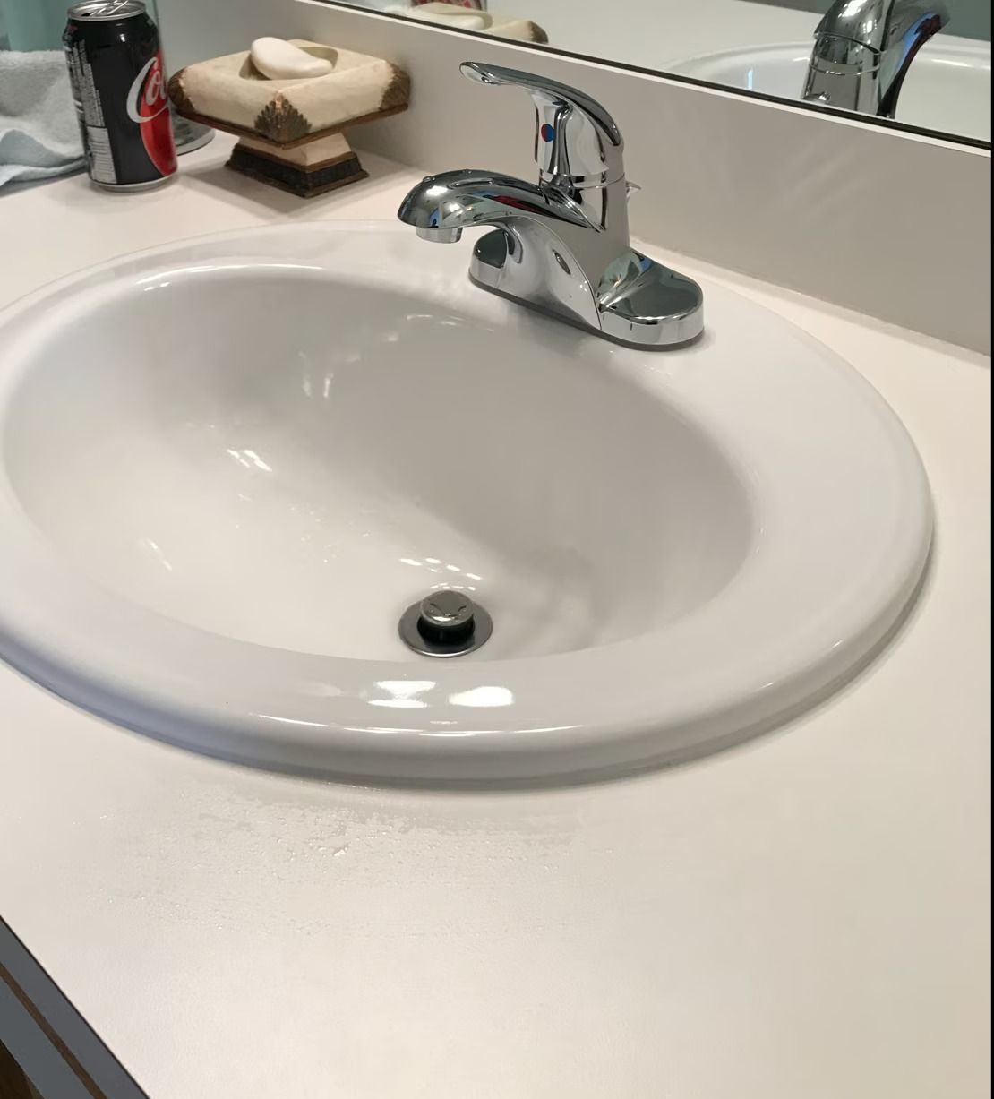 A bathroom sink with a can of coke on the counter