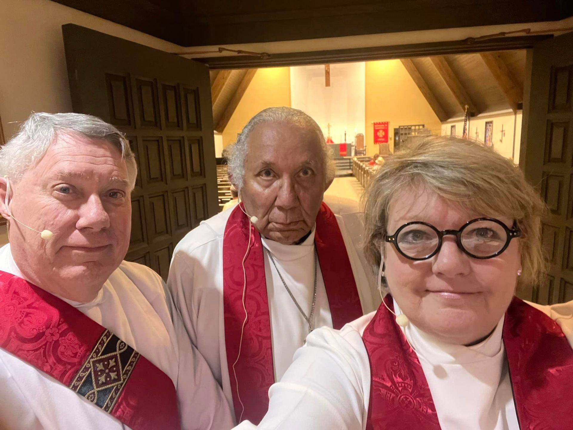 two men and a woman pose for a picture in a church