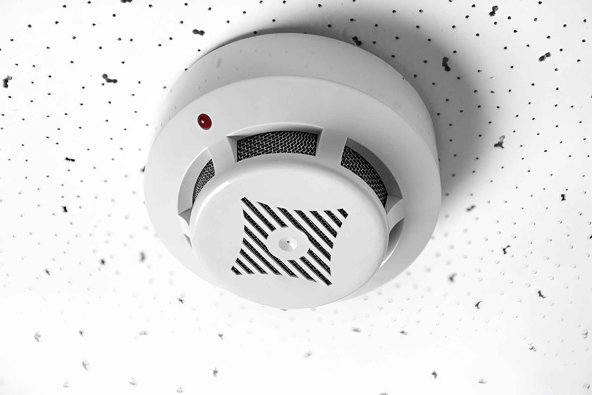 White Ceiling-mounted Smoke Detector With Red Light, on a White Textured Ceiling — Lahtinen Electrical & Refrigeration in Ingham, QLD