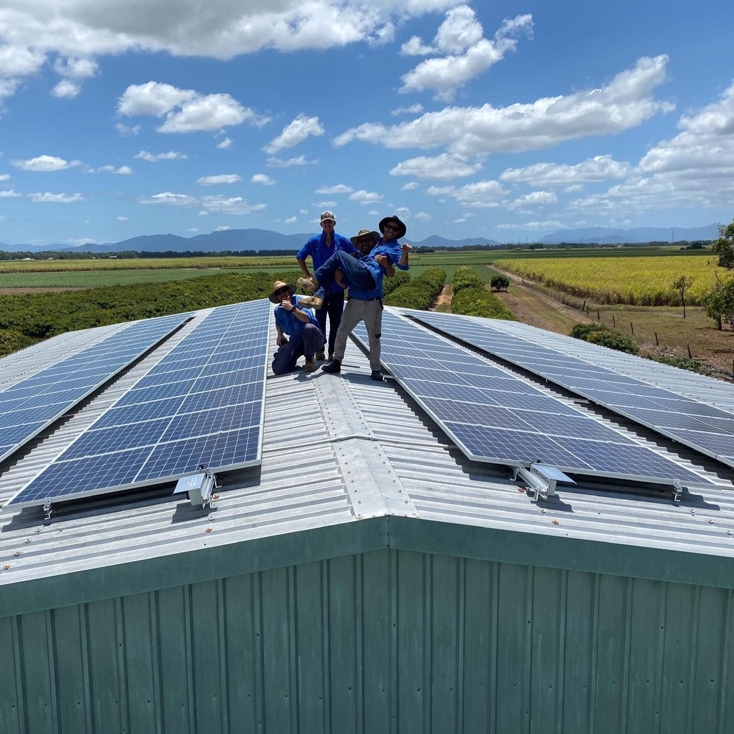 People on a rooftop with solar panels, blue sky, and green fields in the background.— Lahtinen Electrical & Refrigeration in Ingham, QLD