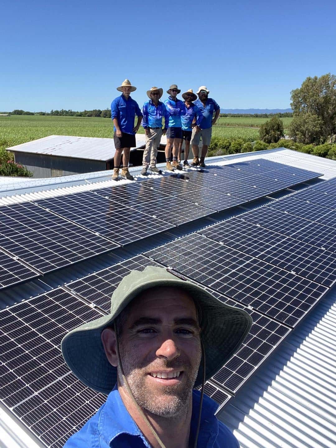 Man on Roof Takes Selfie With Crew and Solar Panels. Clear Blue Sky — Lahtinen Electrical & Refrigeration in Ingham, QLD