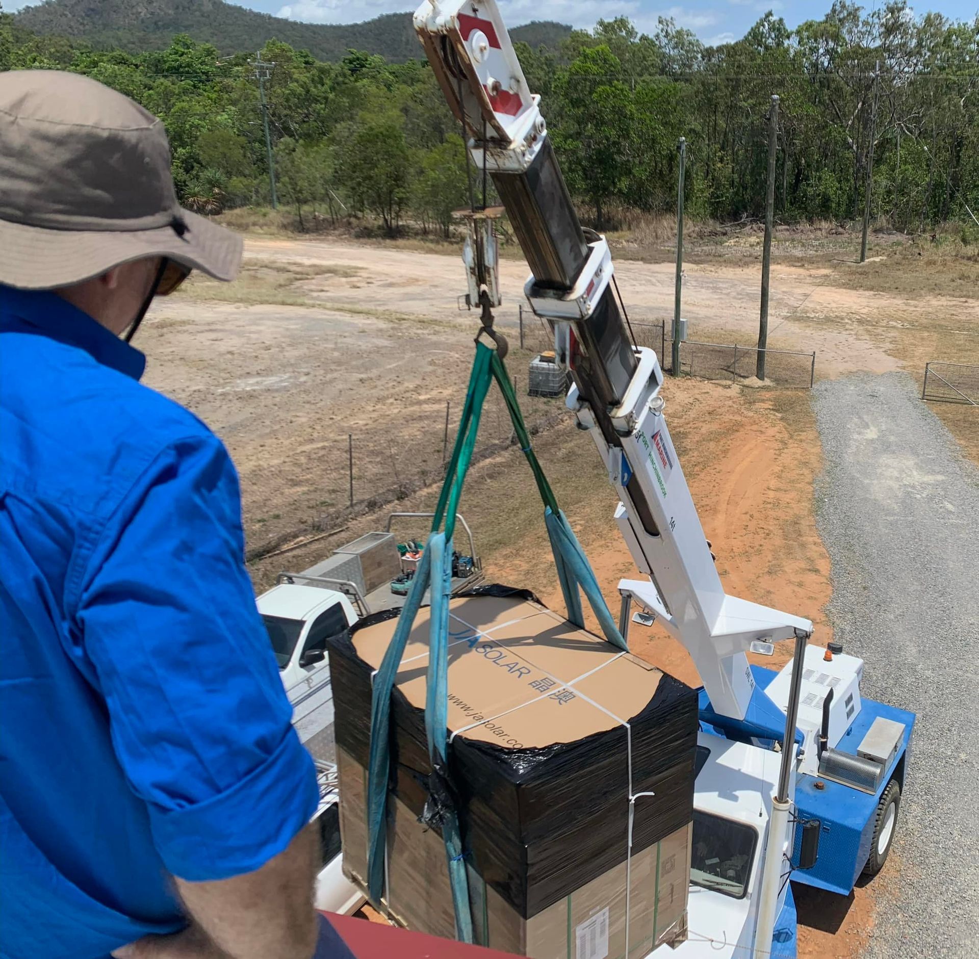 Man Watches a Crane Lift a Large, Boxed Load Onto a Truck — Lahtinen Electrical & Refrigeration in Ingham, QLD