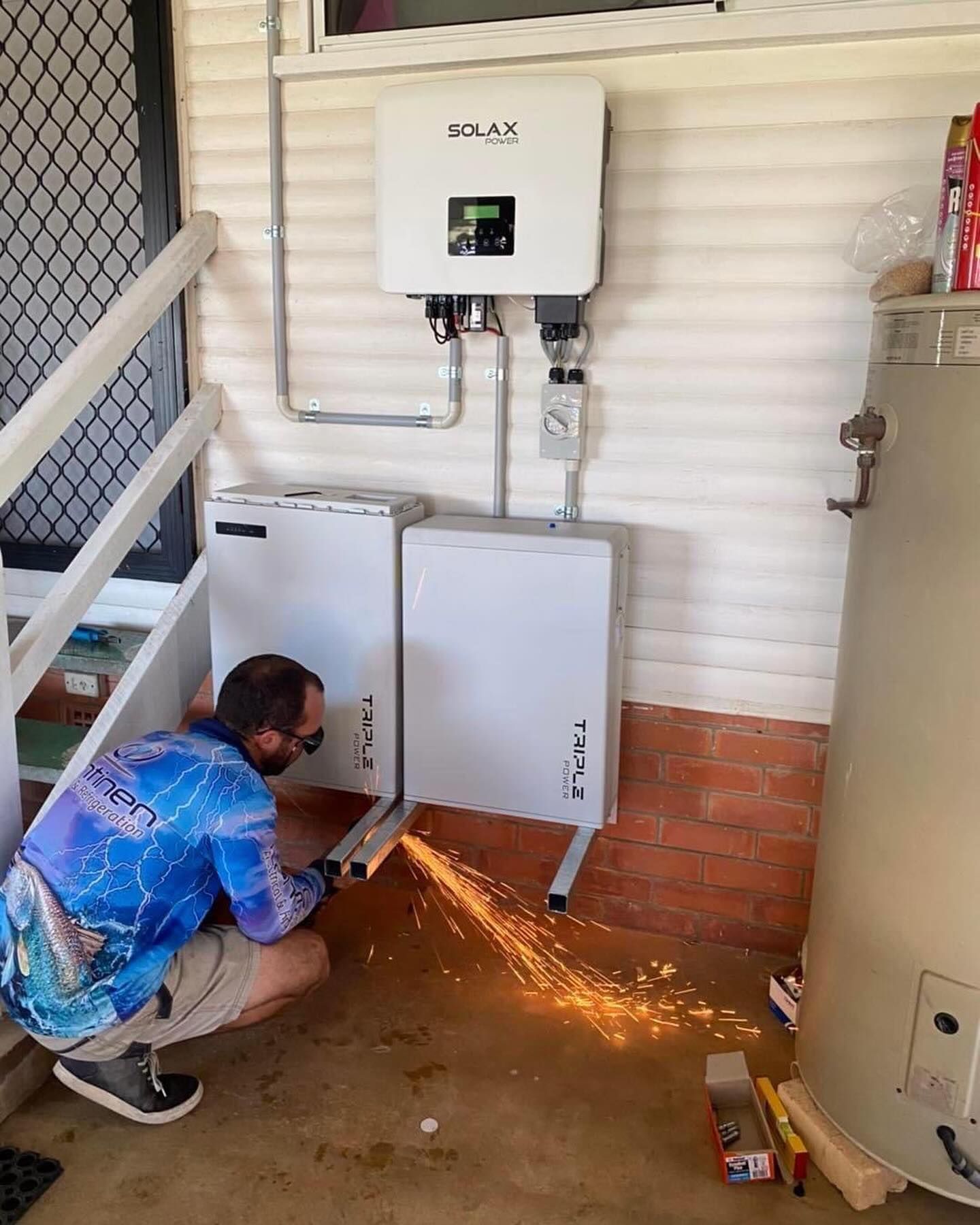 A Person Using a Grinder, Sparks Flying, on a Metal Frame — Lahtinen Electrical & Refrigeration in Ingham, QLD
