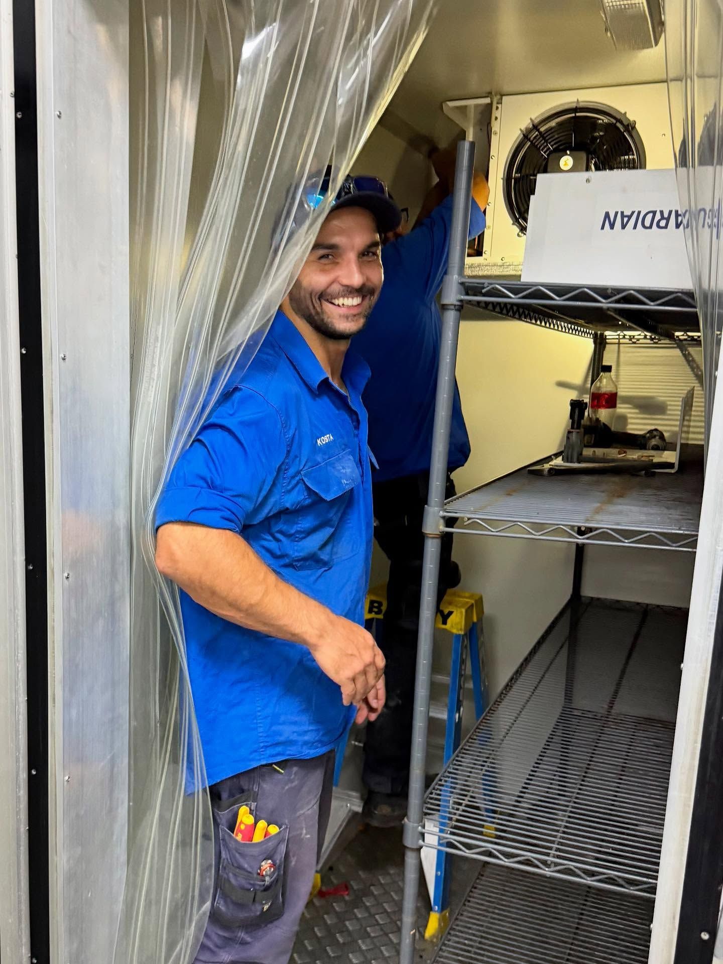 Man in Blue Shirt Smiles, Standing Inside a Walk-in Cooler — Lahtinen Electrical & Refrigeration in Ingham, QLD