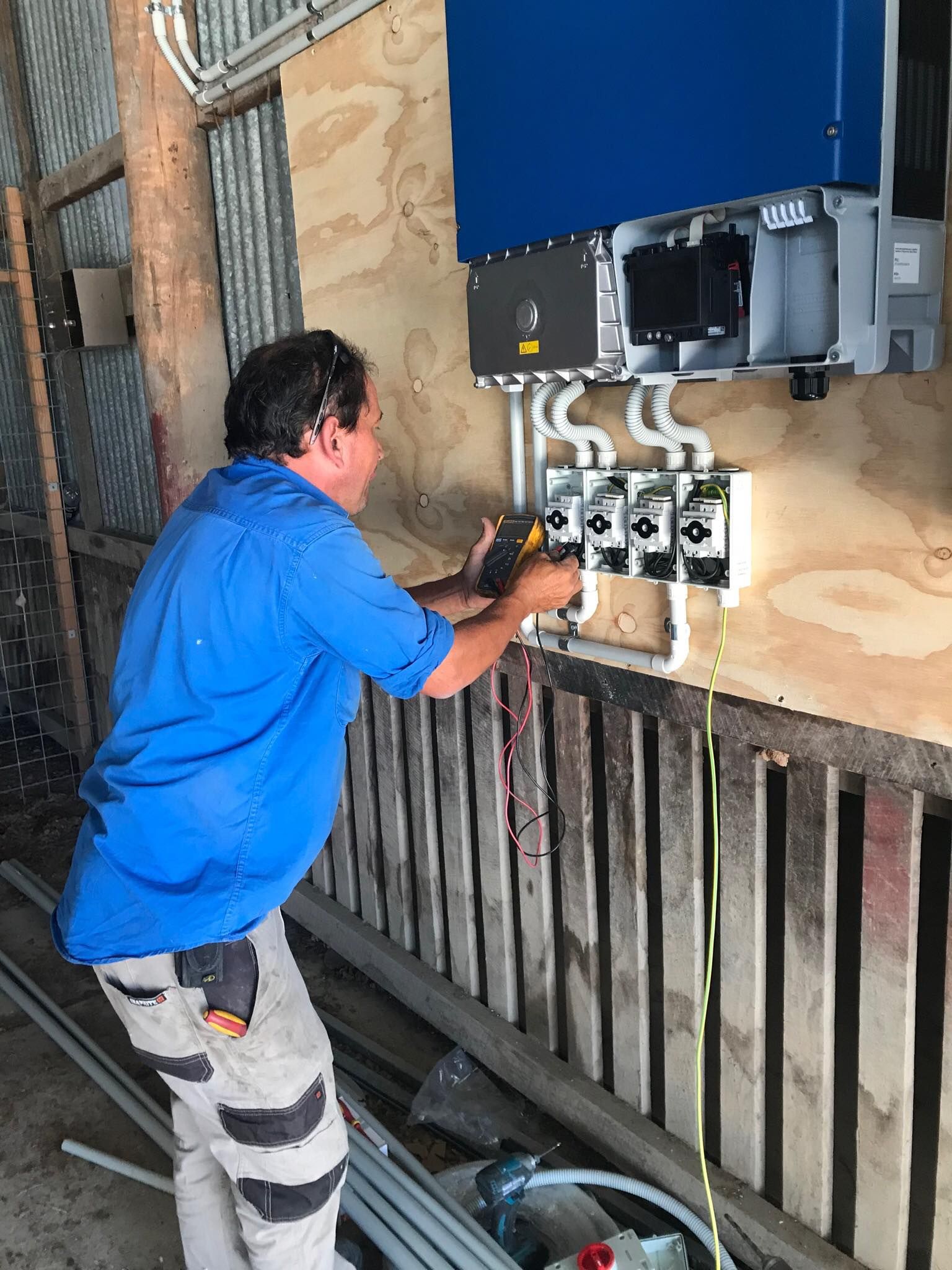 Electrician installing electrical components on a wood wall. Wires and conduit are visible.— Lahtinen Electrical & Refrigeration in Ingham, QLD