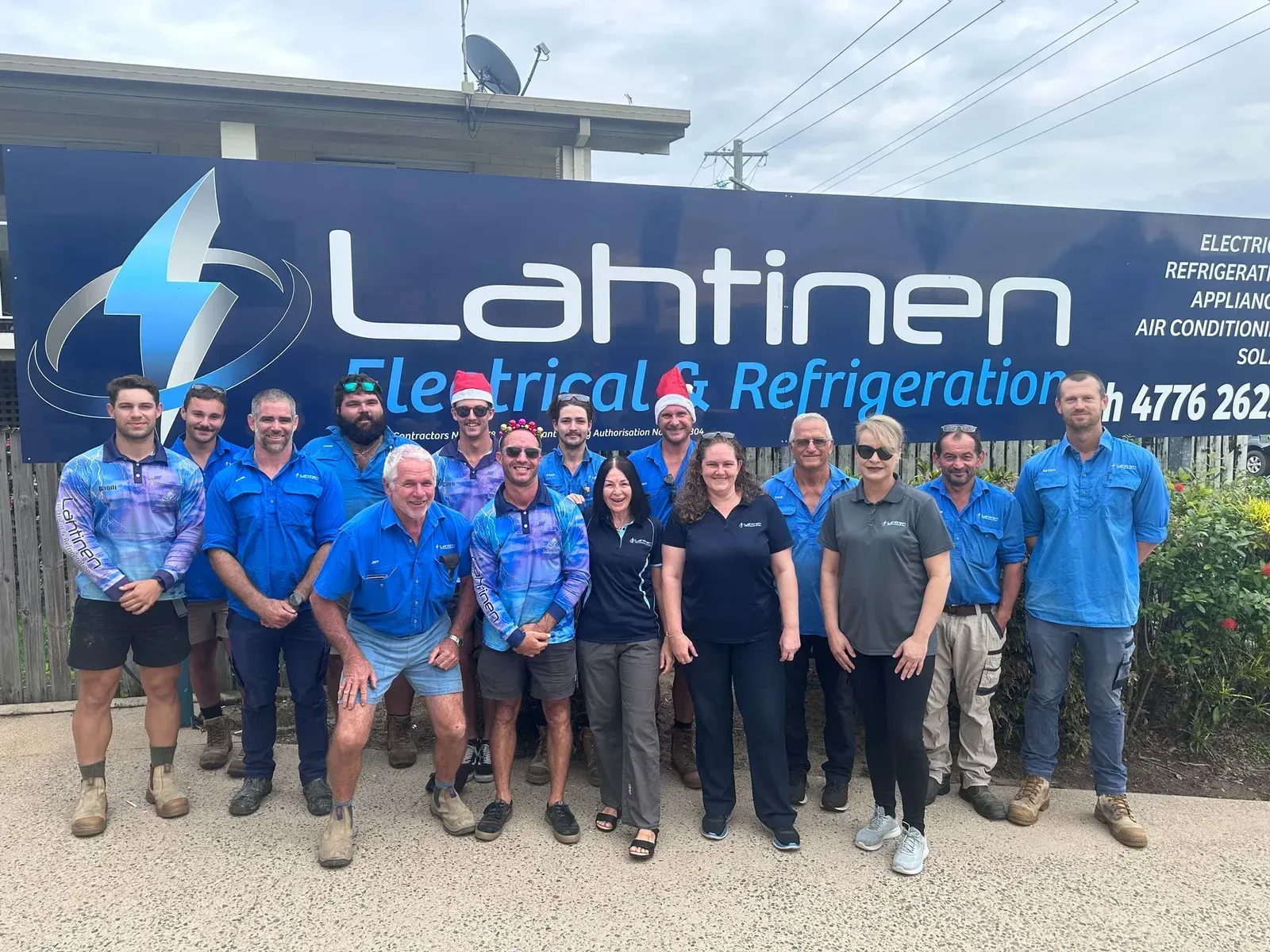 Group of People in Blue Shirts in Front of a Sign for Lahtinen — Lahtinen Electrical & Refrigeration in Ingham, QLD