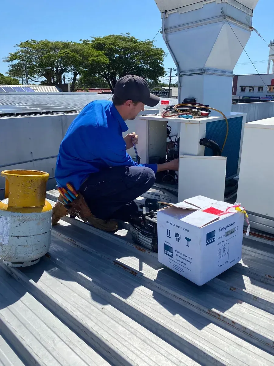 Hvac Technician in Blue Shirt Works on Rooftop Equipment — Lahtinen Electrical & Refrigeration in Ingham, QLD