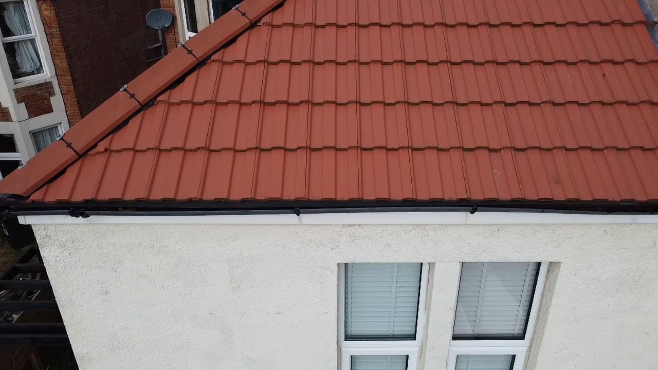 Red tiled roof above a white house wall with two windows