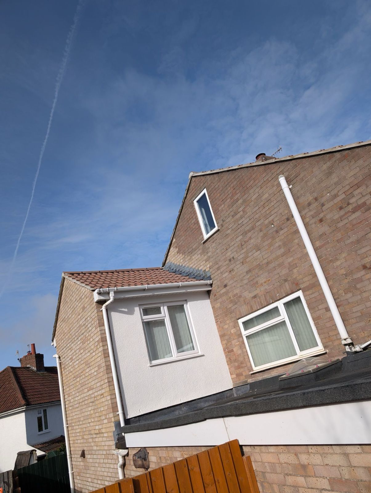 Tilted view of suburban brick houses under a blue sky with thin clouds
