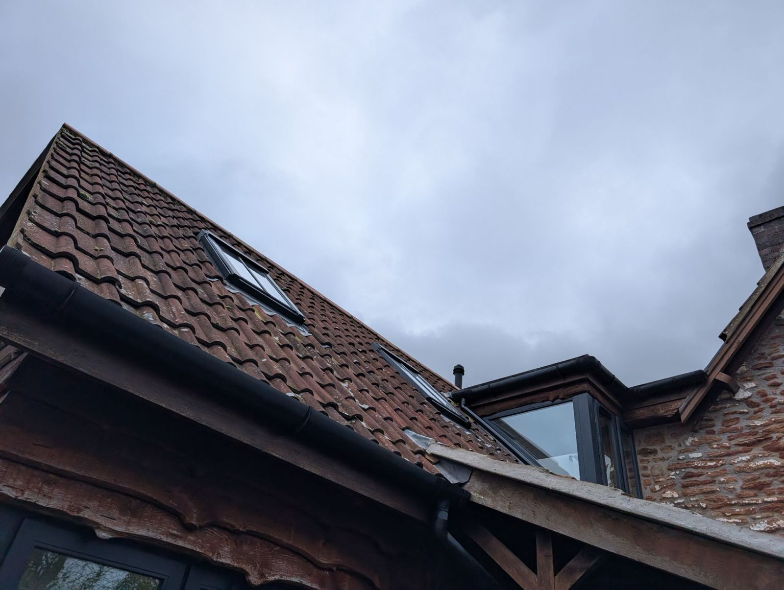 Tiled rooftops and a small dormer window against a cloudy sky