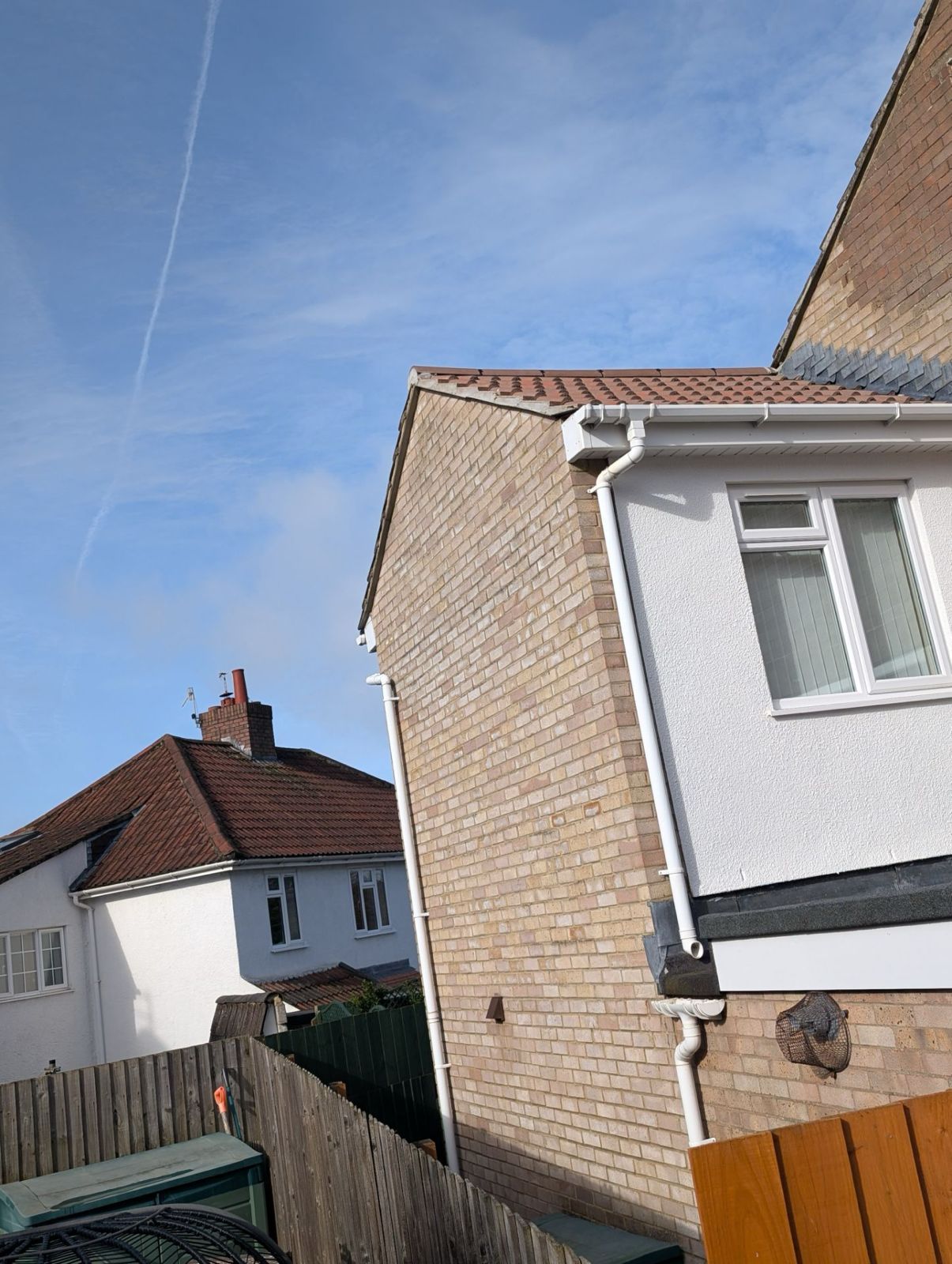 Residential street with brick and white houses under a blue sky, viewed at an angle