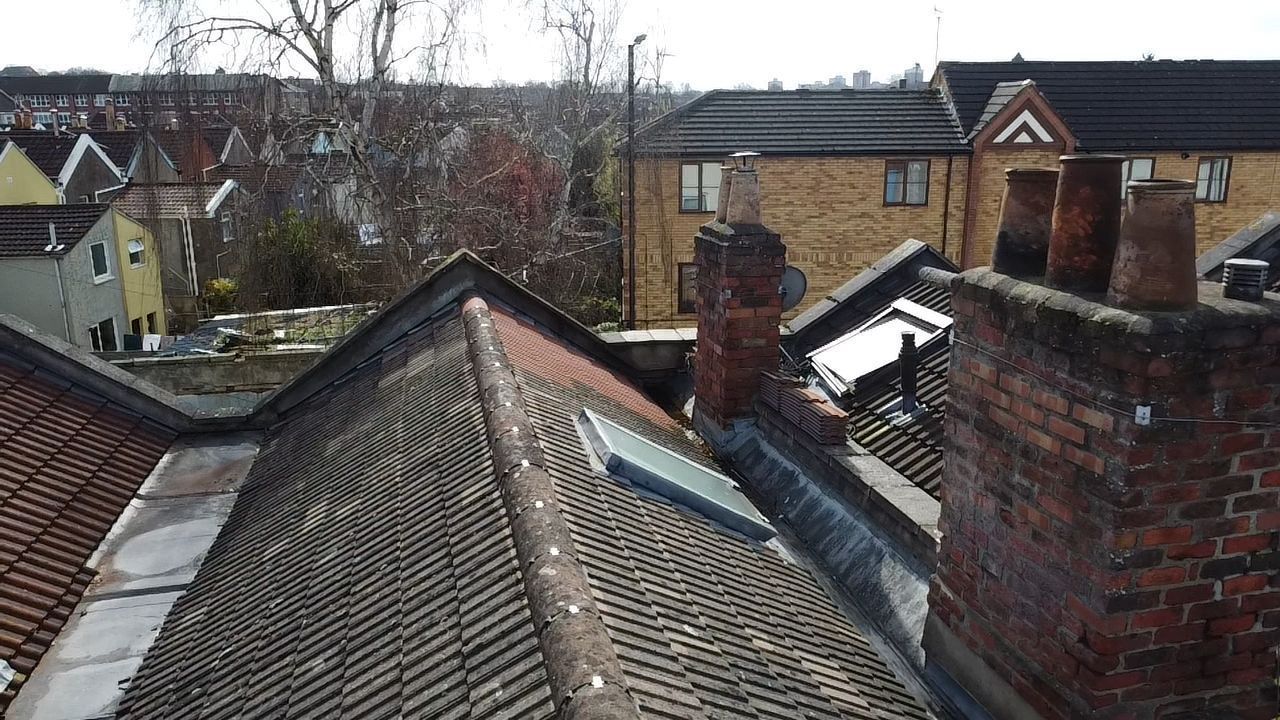View over tiled rooftops and brick chimneys in a residential neighborhood on a cloudy day