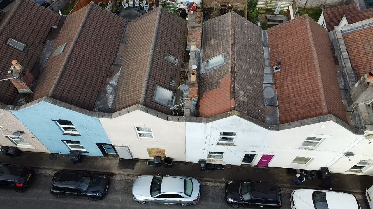Aerial view of row houses with red-tiled roofs and parked cars along the street