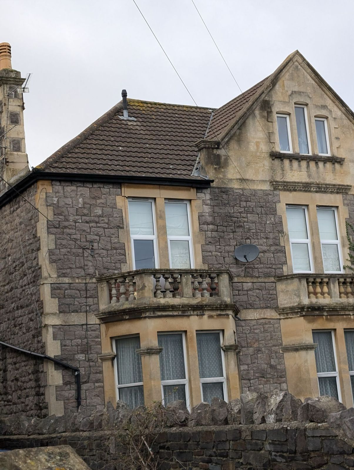 Stone house with a tiled roof and arched windows under an overcast sky