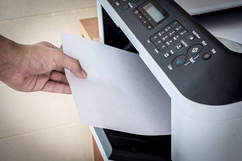 mano che ritira un foglio da una stampante