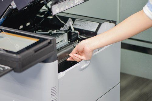 mano di una donna che tira lo sportello di una stampante fotocopiatrice