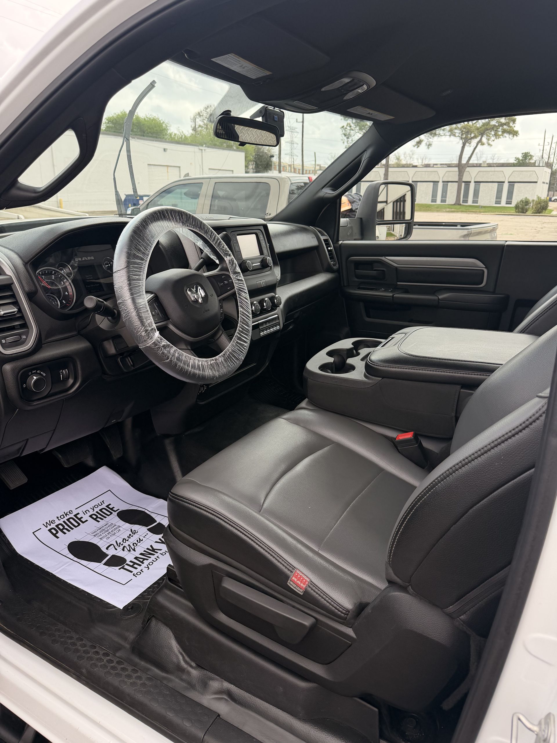 Driver’s seat and dashboard of a black truck interior with a paper mat on the floor.