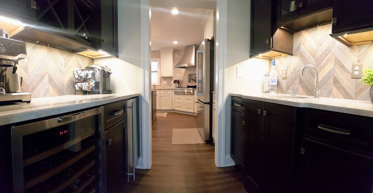 A kitchen with black cabinets and stainless steel appliances and a wine cooler.