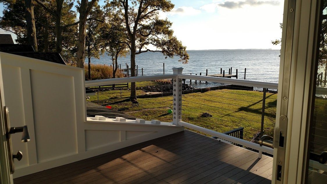 A balcony with a view of the ocean and trees.