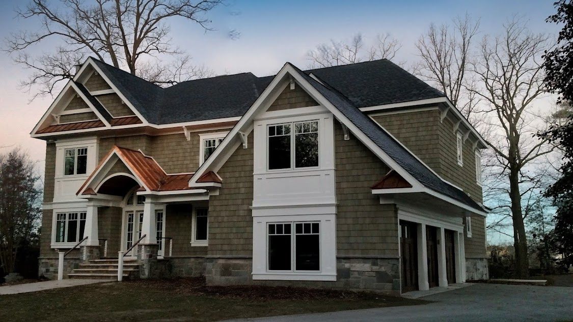 A large house with a gray roof is surrounded by trees