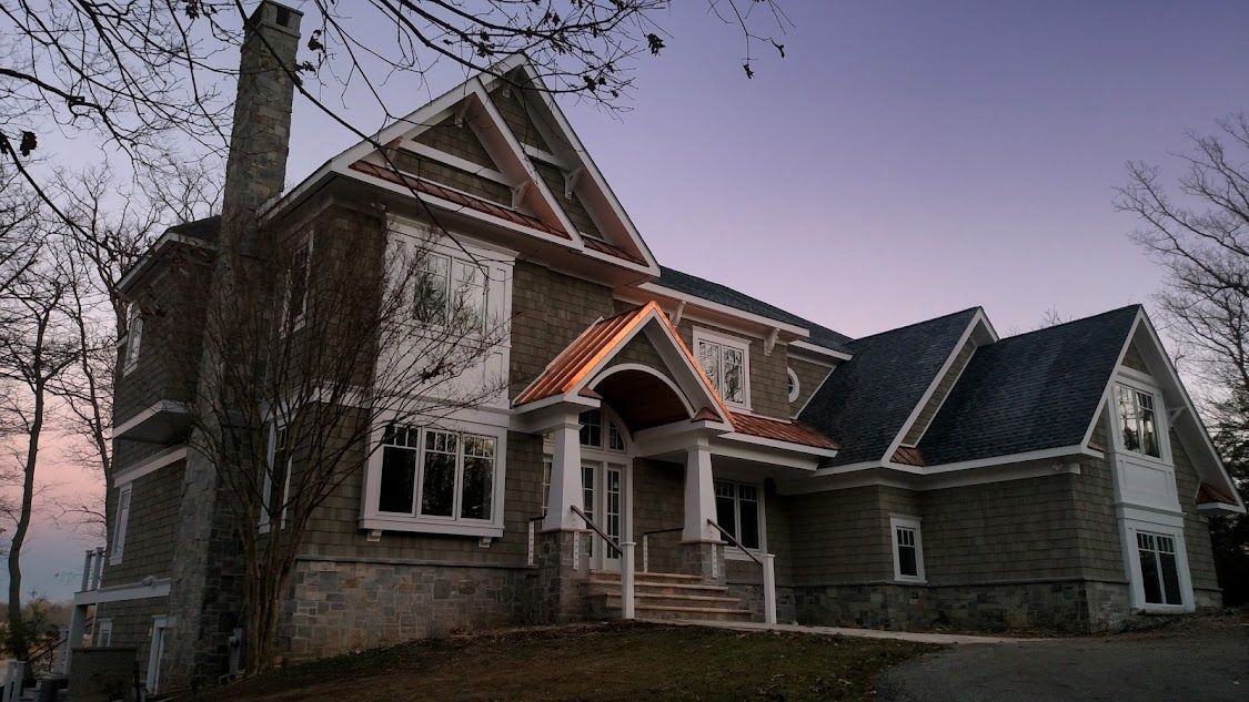 A large house with a purple sky in the background is surrounded by trees.