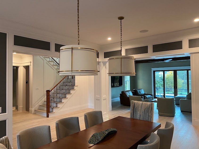 A dining room with a table and chairs and a staircase in the background.
